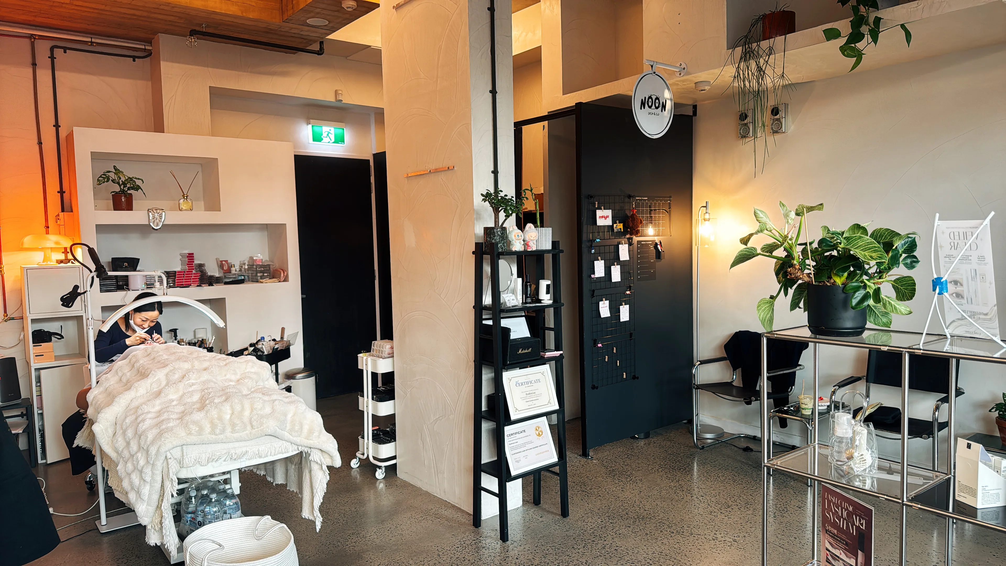 The Noon Lash & Co studio on Nicholson Street — warm plaster walls, timber ceiling, terrazzo floors and the round NOON sign at the door
