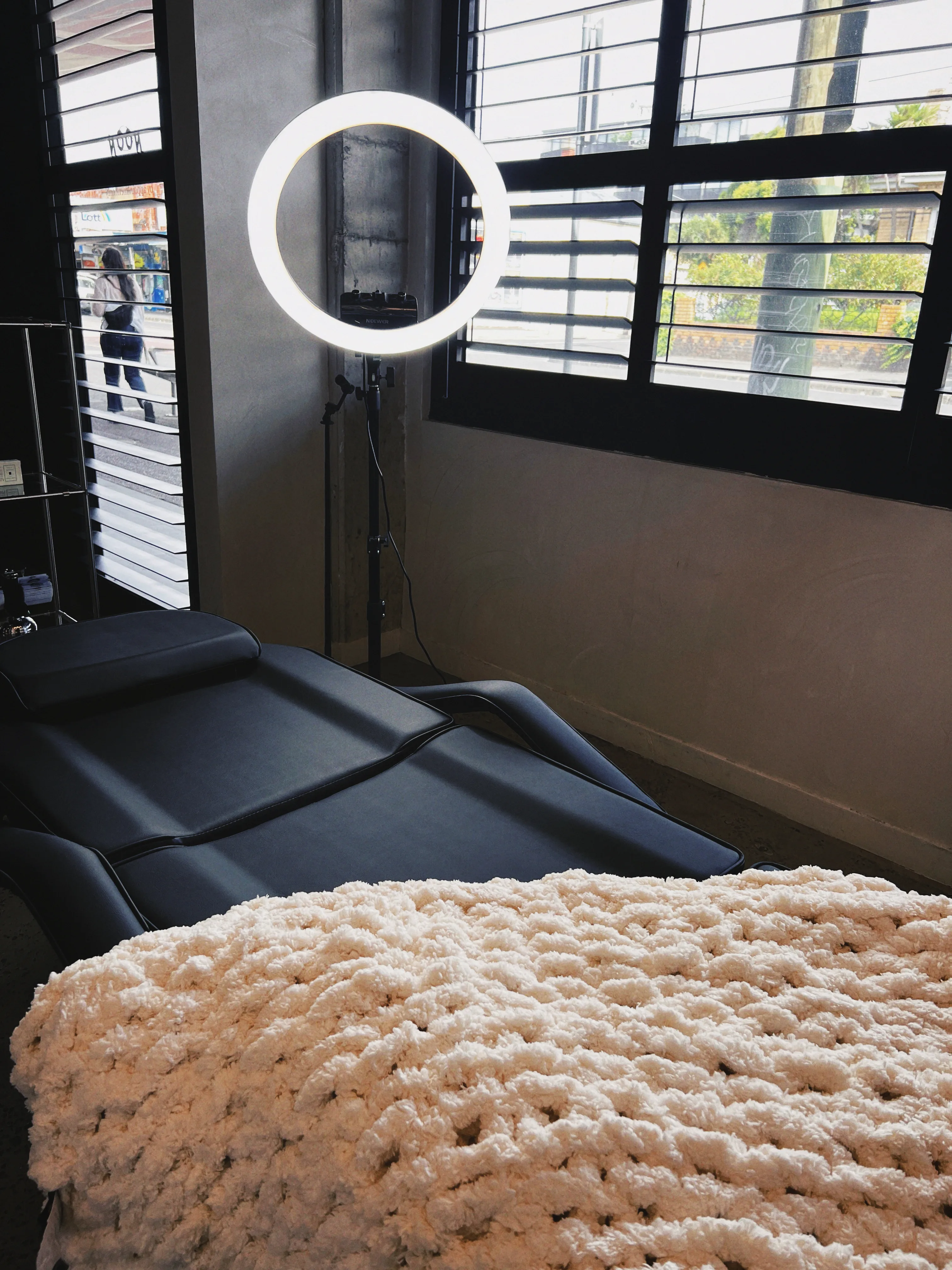 The treatment bed at the louvred windows looking out onto Nicholson Street, cream chunky-knit throw in the foreground