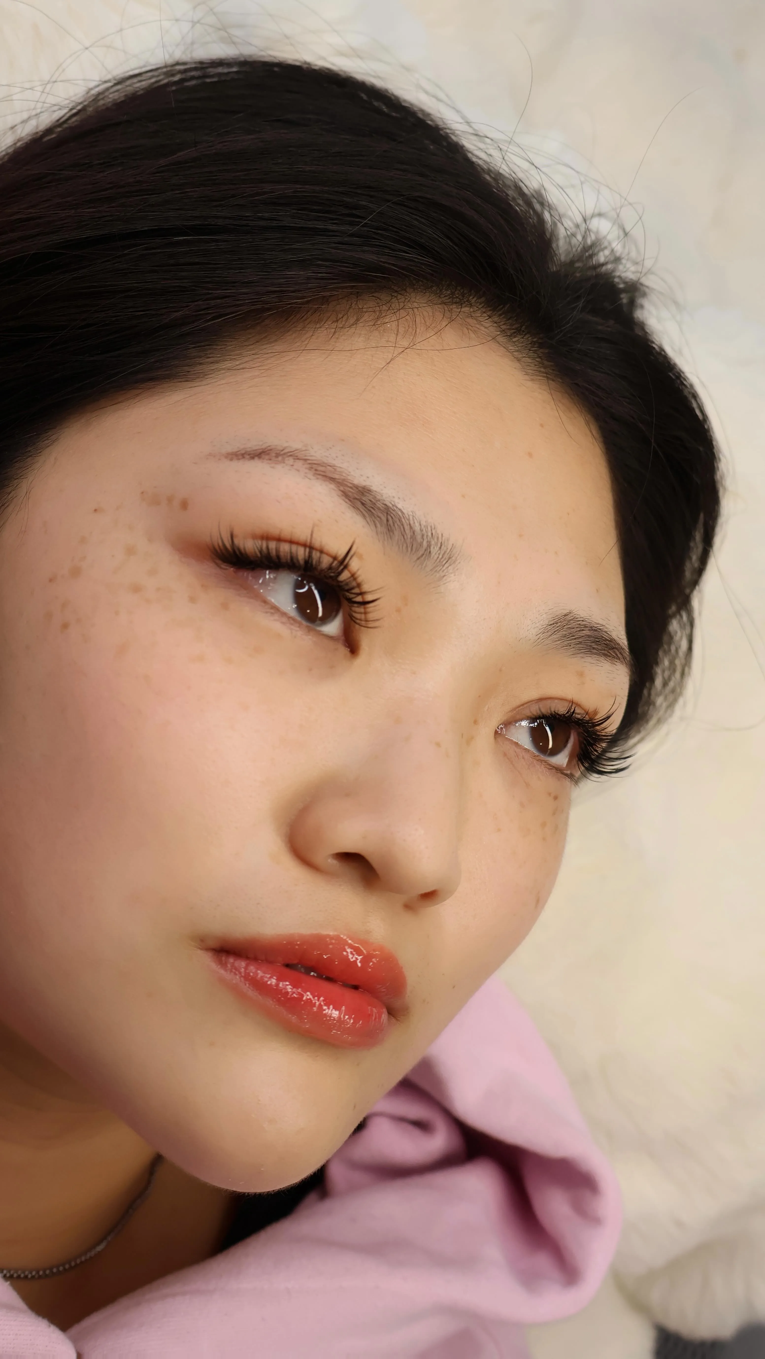 A client resting on the lash bed with a finished natural wispy extension set in warm daylight