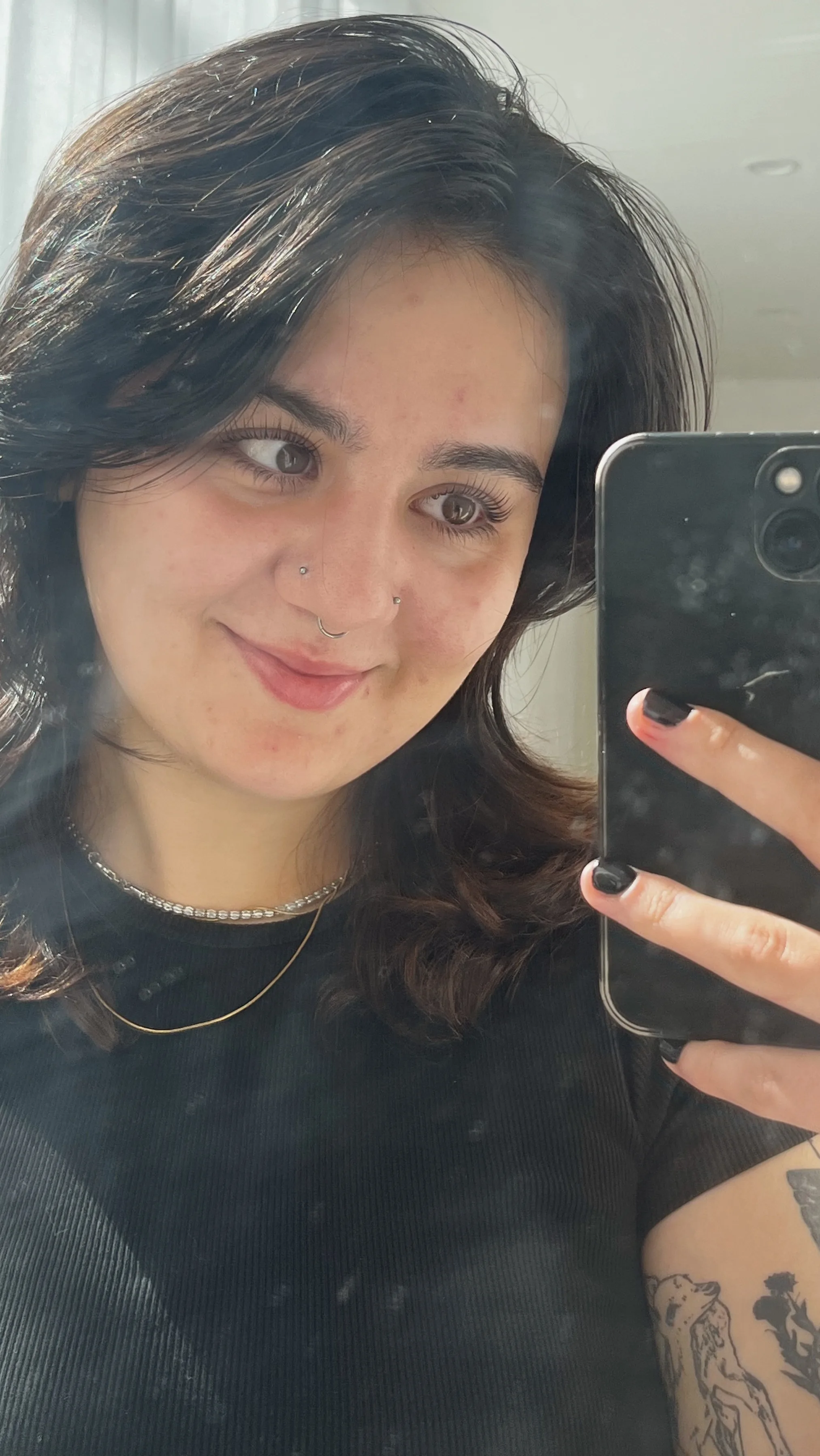 A client's mirror selfie showing her finished lash set, smiling
